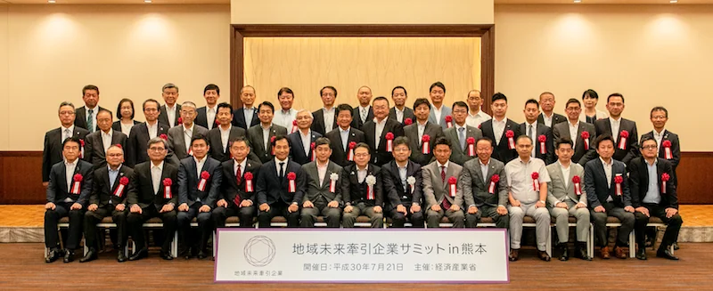 地域未来牽引企業サミットの集合写真。前列中央が経済産業大臣、前列右から4人目が当社代表